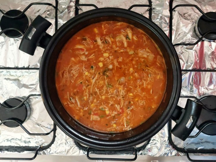 Uma panela cozinhando frango desfiado.