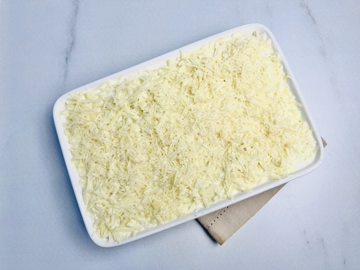 Refratário preenchido por camadas de molho branco, massa de lasanha, frango desfiado e finalizado com queijo mussarela e parmesão ralados.
