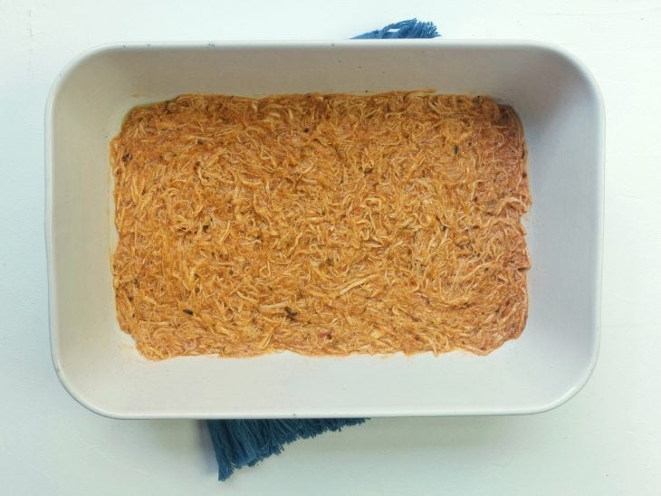 Um refratário com uma camada de molho para lasanha.