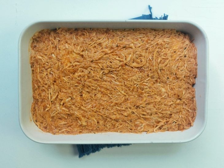 Um refratário com lasanha de frango com queijo antes de assar.