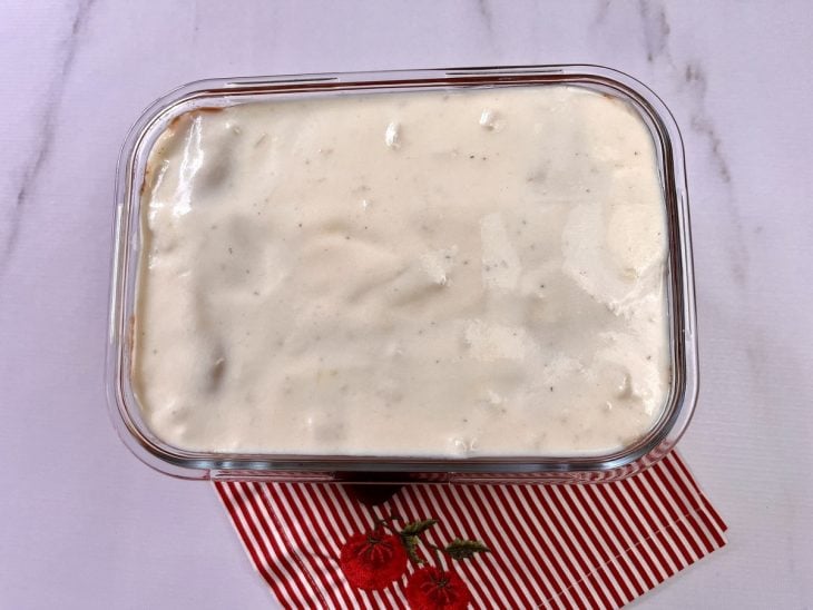 Um refratário forrado com lasanha coberta com molho branco.