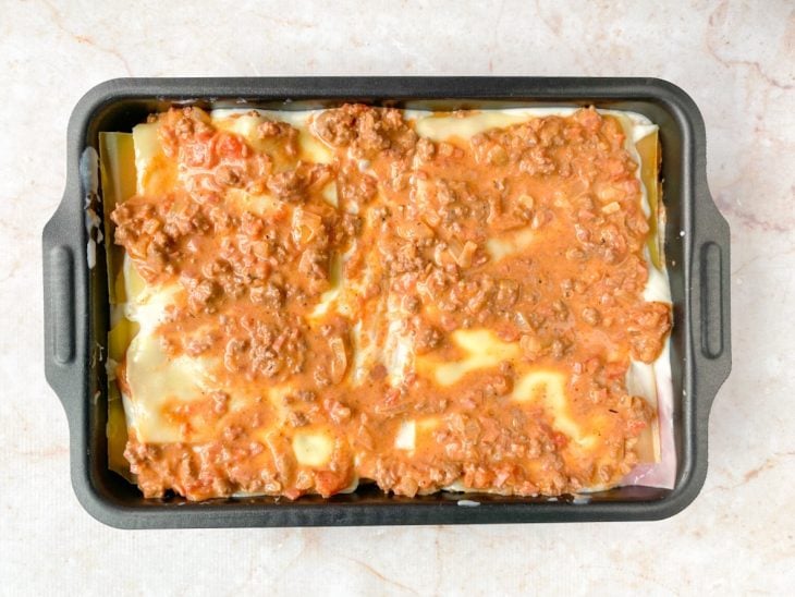 Camada de queijo e molho bolonhesa.