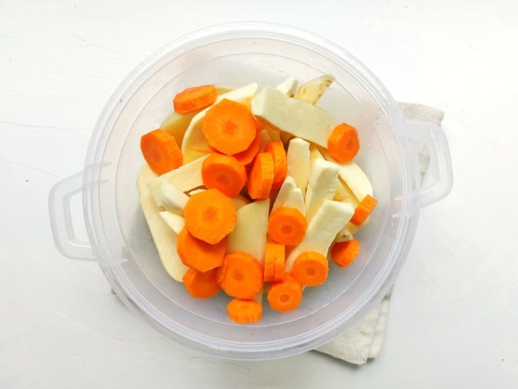 Um recipiente com os palitos de batatas e rodelas de cenoura.