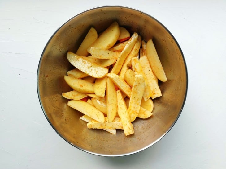 Um recipiente com as batatas e cenouras temperadas.