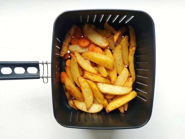Uma cesta de airfryer contendo legumes crocantes.