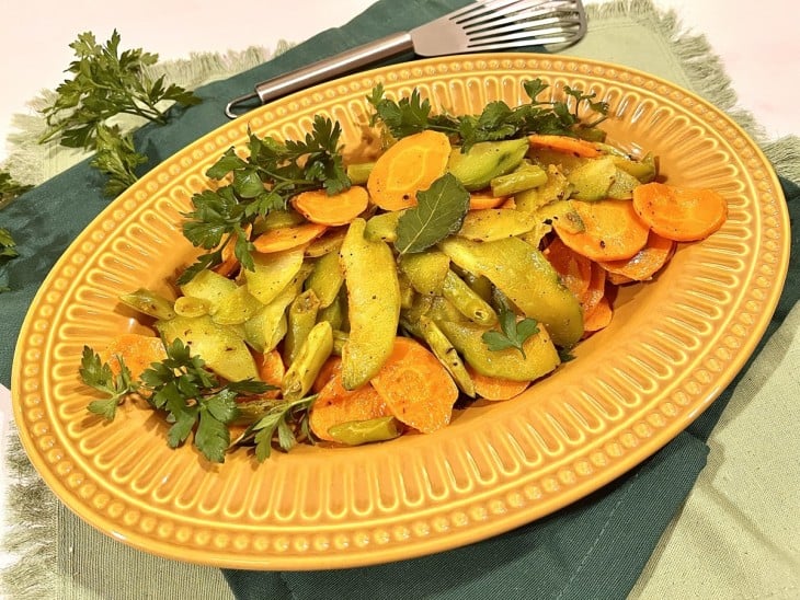 Prato laranja com legumes salteados.