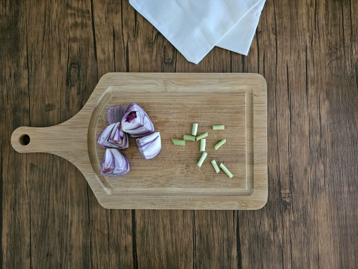 Uma tábua com cebola e talo de salsão picados.