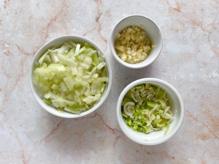 Recipientes com cebola, alho e alho-poró picados.