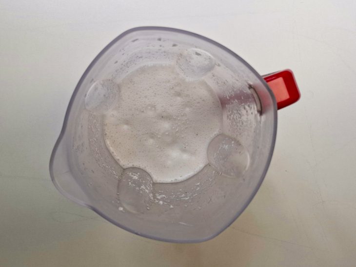 Coco sendo batido no liquidificador com água morna.