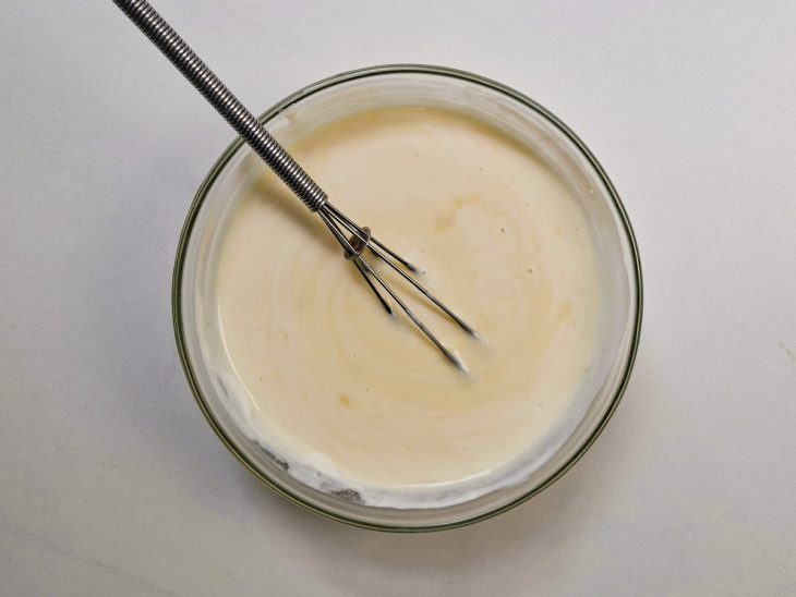 Chocolate branco derretido com creme de leite formando uma ganache lisa.