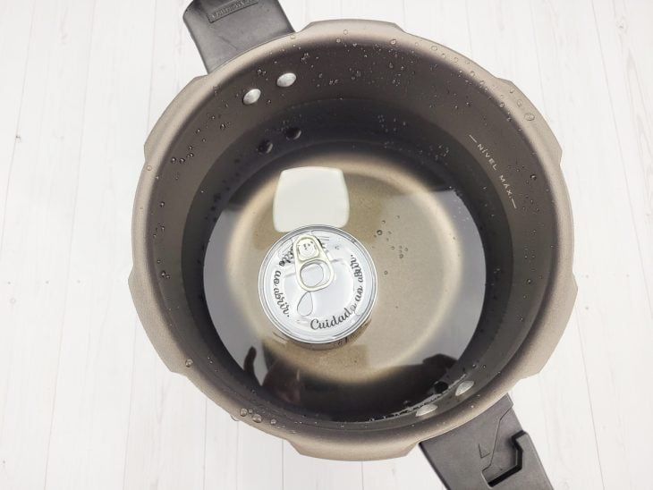 Uma panela de pressão contendo uma lata de leite condensado coberto com água.