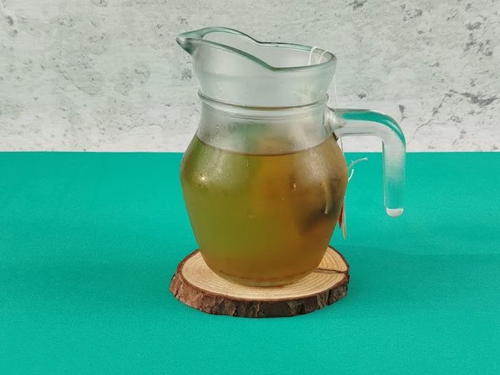 Sachês de chá infusionando em uma jarra de vidro com água.