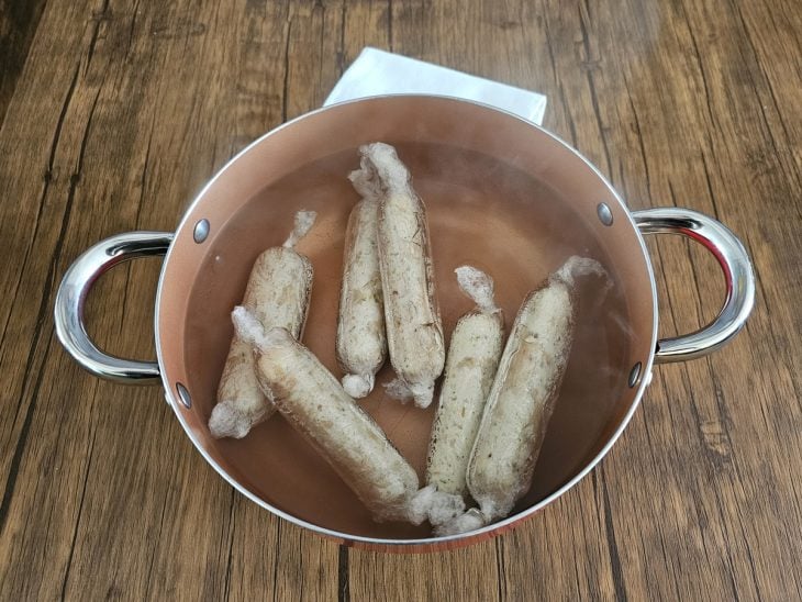 Linguiças de frango enroladas em plástico filme cozinhando.