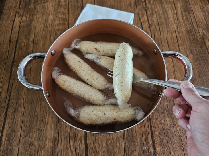 Linguiças de frango enroladas em plástico filme cozinhando.