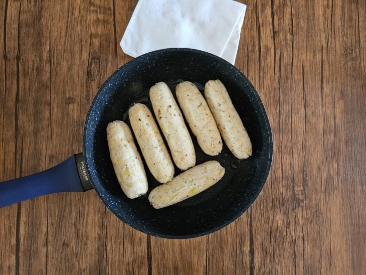 Linguiças de frango em uma frigideira.