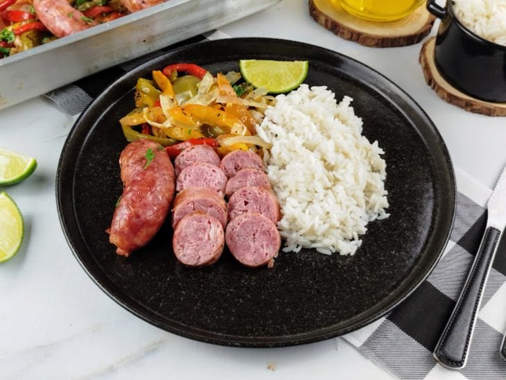 Prato com uma porção de arroz, luinguiças cortadas e pimentões.