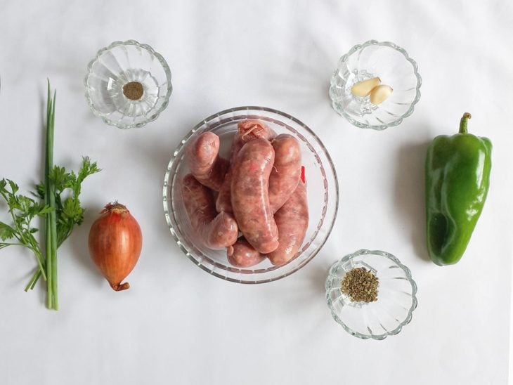 Ingredientes para a receita de linguiça toscana grelhada na frigideira reunidos em uma bancada.