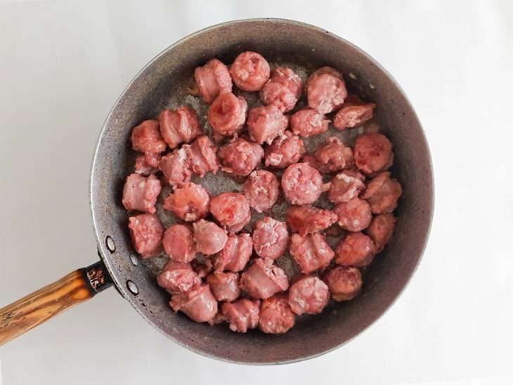 Linguiça toscana em pedaços menores adicionada na frigideira.