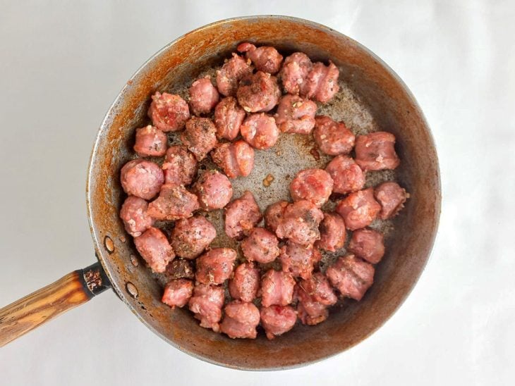 Alho, orégano e pimenta-do-reino adicionados e incorporados na linguiça toscana da frigideira.
