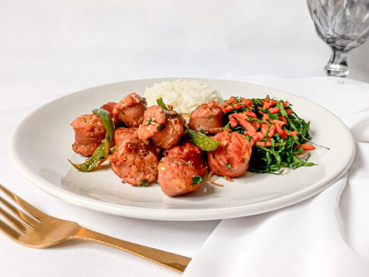 Linguiça toscana grelhada na frigideira servida com arroz e couve, em um prato redondo e branco.