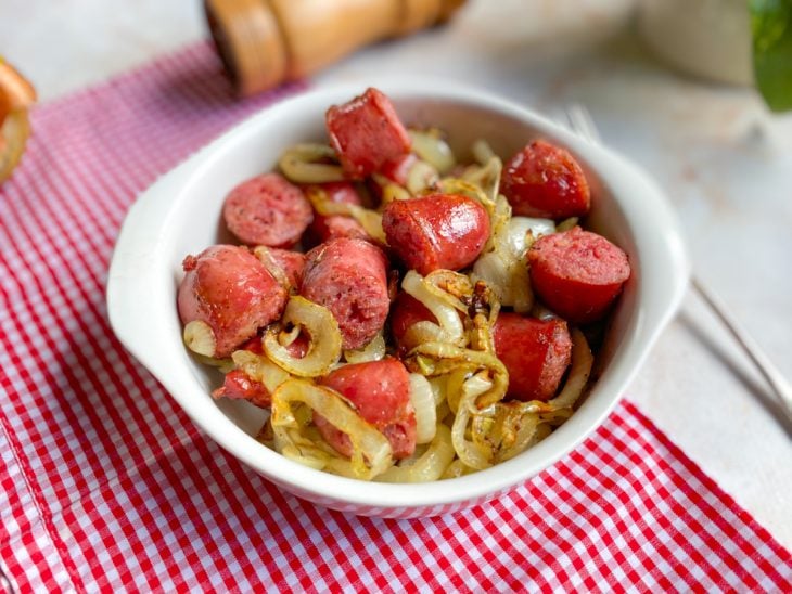 Linguiça toscana acebolada pronta para consumo em uma travessa de porcelana.