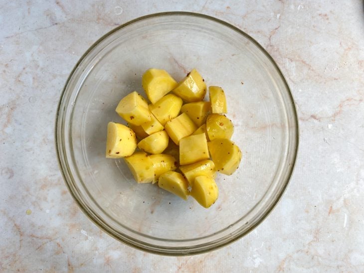 Batatas cortadas e temperadas em uma tigela.