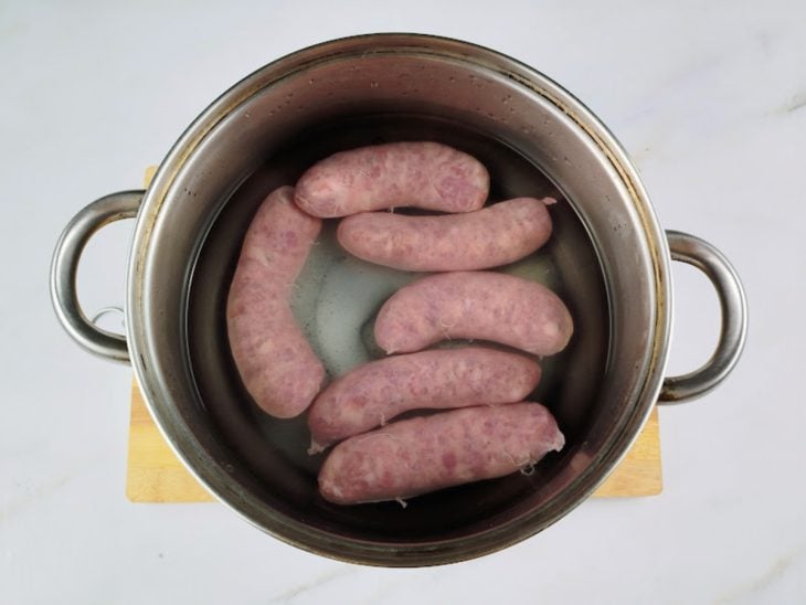 Gomos de linguiça cobertos por água para cozinhar.