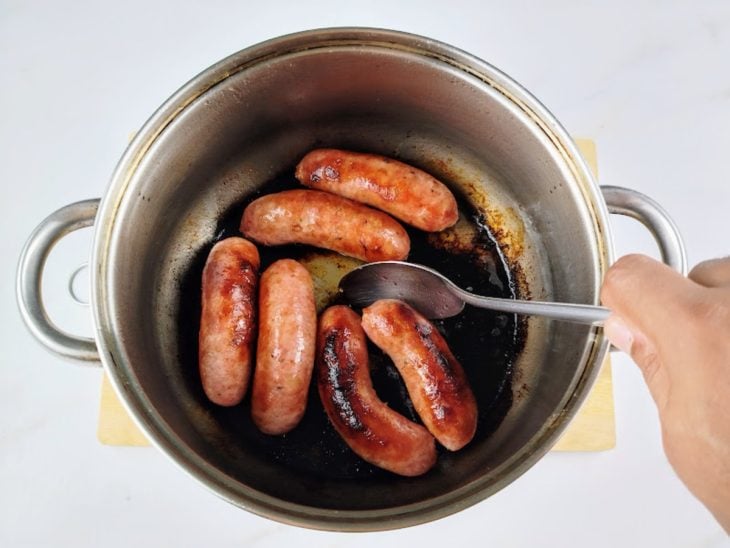Gomos de linguiça mexidos com uma colher.