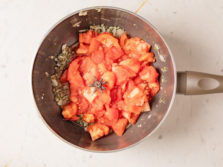 Tomates e estrela de anis em uma panela.