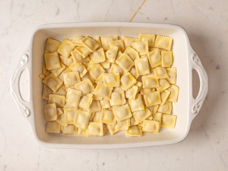Raviolis cozidos dispostos em uma travessa com azeite por cima.