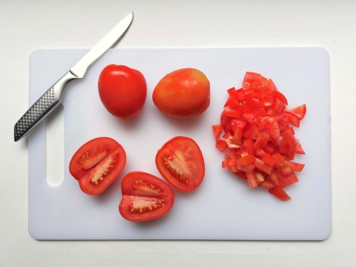Tomates cortados em cubinhos em uma tábua.