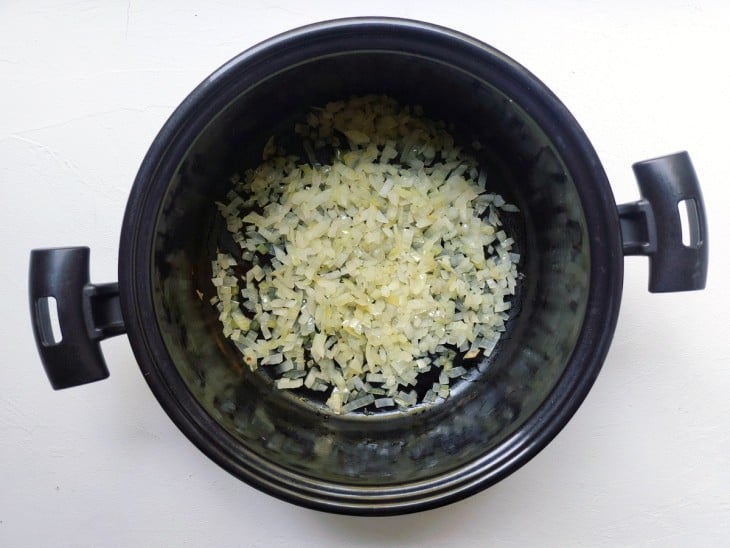 Uma panela contendo azeite e cebola.