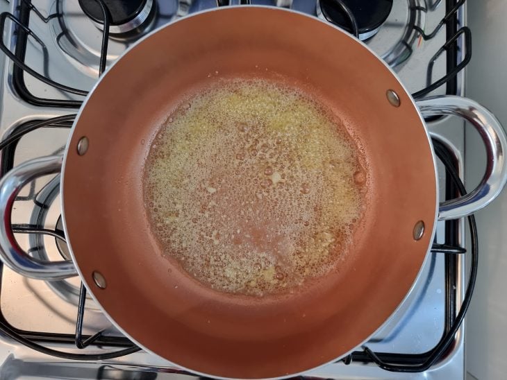 Azeite e manteiga em uma panela de fundo laranja.