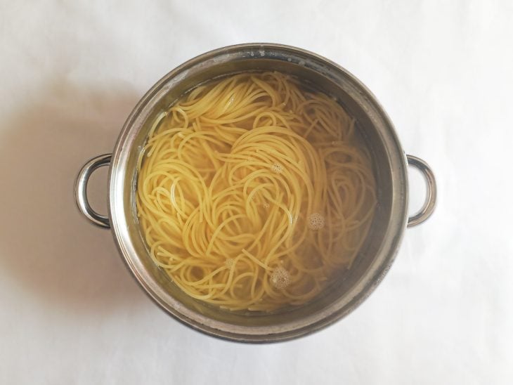 Macarrão cozido em água fervente numa panela.