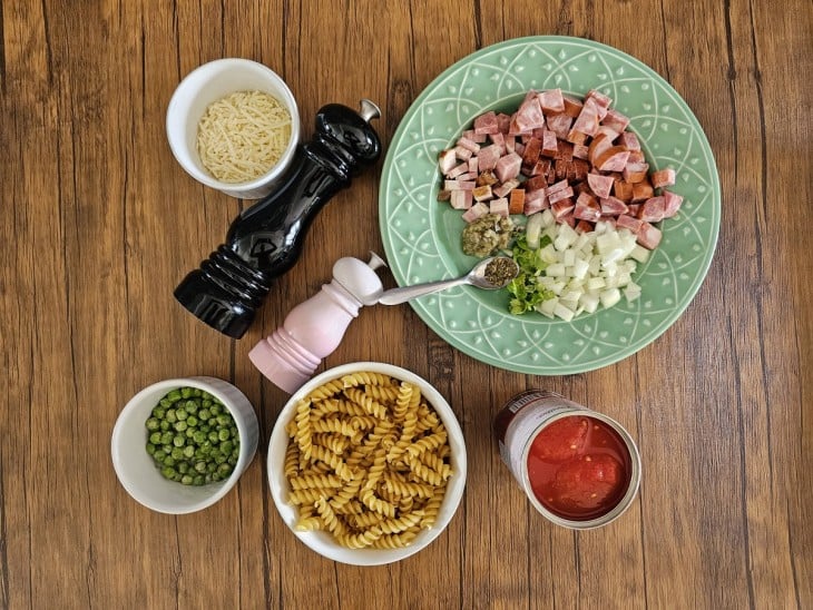 Todos os ingredientes da receita reunidos: macarrão, calabresa, bacon, cebola, molho e temperos.