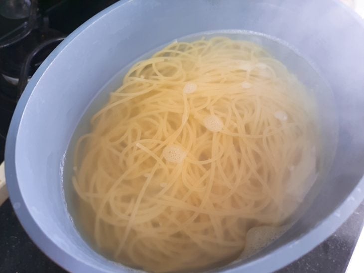 Uma tigela com água e o macarrão cozido.