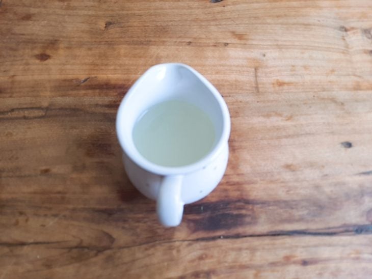 Um recipiente com raspas de limão, parmesão ralado, suco de limão, azeite e pimenta.