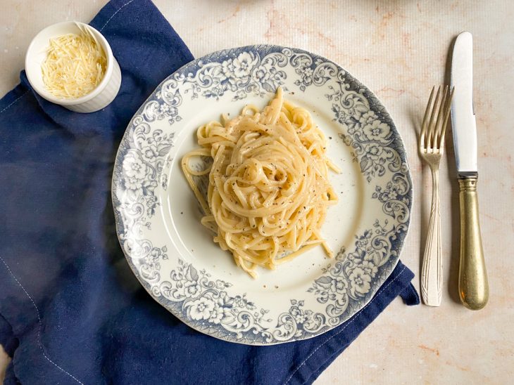 Porção de macarrão cacio e pepe pronto para consumo em um prato.