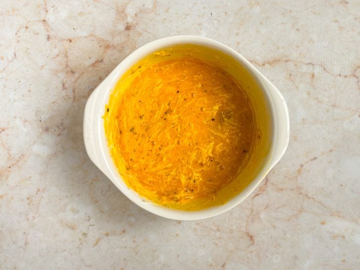Mistura de ovo, queijo parmesão ralado, gema e pimenta-do-reino em uma tigela.