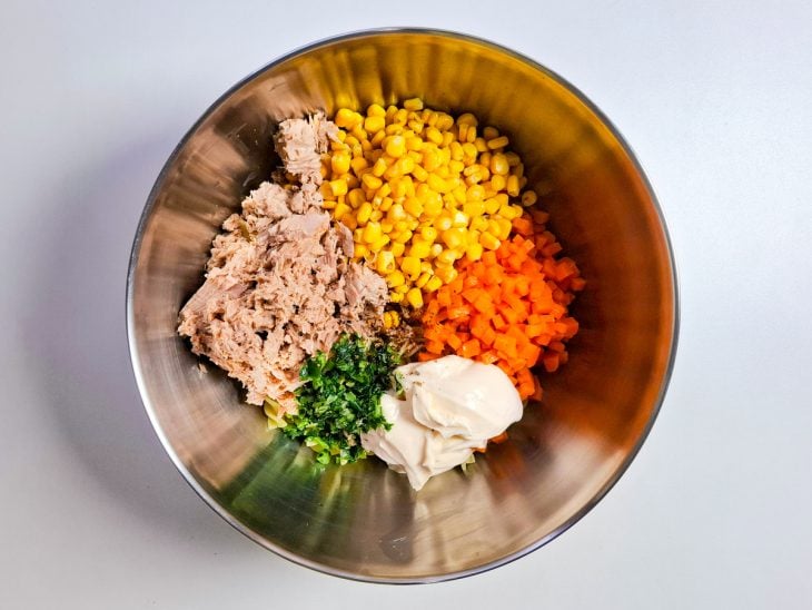 Ingredientes adicionados no recipiente com macarrão cozido.
