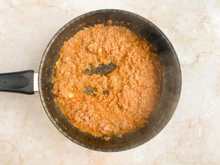 adição de atum e molho de tomate ao refogado para fazer o molho de macarrão.