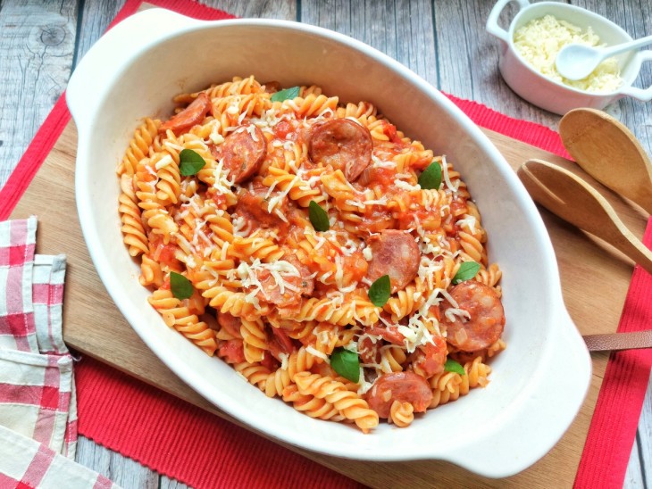 Macarrão com calabresa servido em travessa branca.