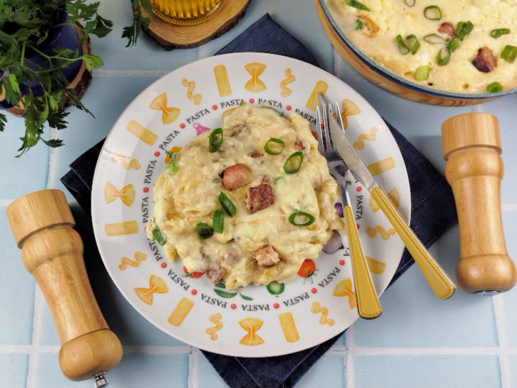 Macarrão com creme de batata e bacon pronto para consumo em um prato.