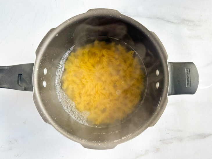 Macarrão sendo cozido em panela com água fervente até ficar al dente.