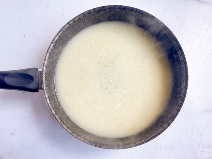 Caldo do cozimento do frango sendo adicionado aos poucos enquanto a mistura é mexida com fouet.