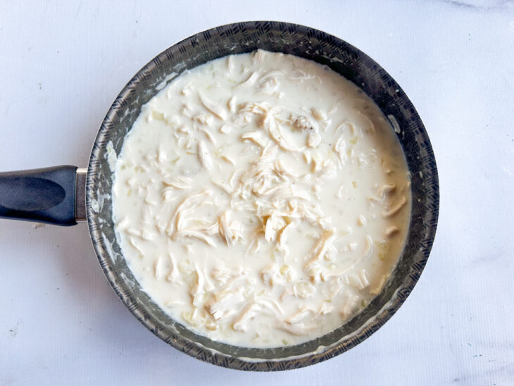 Creme de leite sendo misturado delicadamente ao preparo.