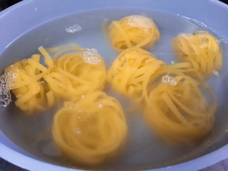 Uma panela com o macarrão na água.