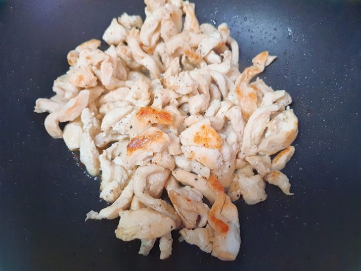 Uma frigideira com o frango a dourar.