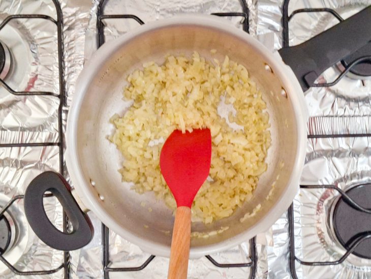 Alho e cebola sendo refogados numa panela com azeite.