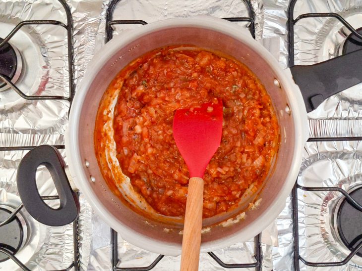 Molho de tomate e orégano adicionados na panela.